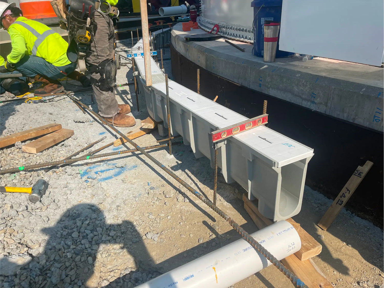 Construction site with workers installing radius trench drain system