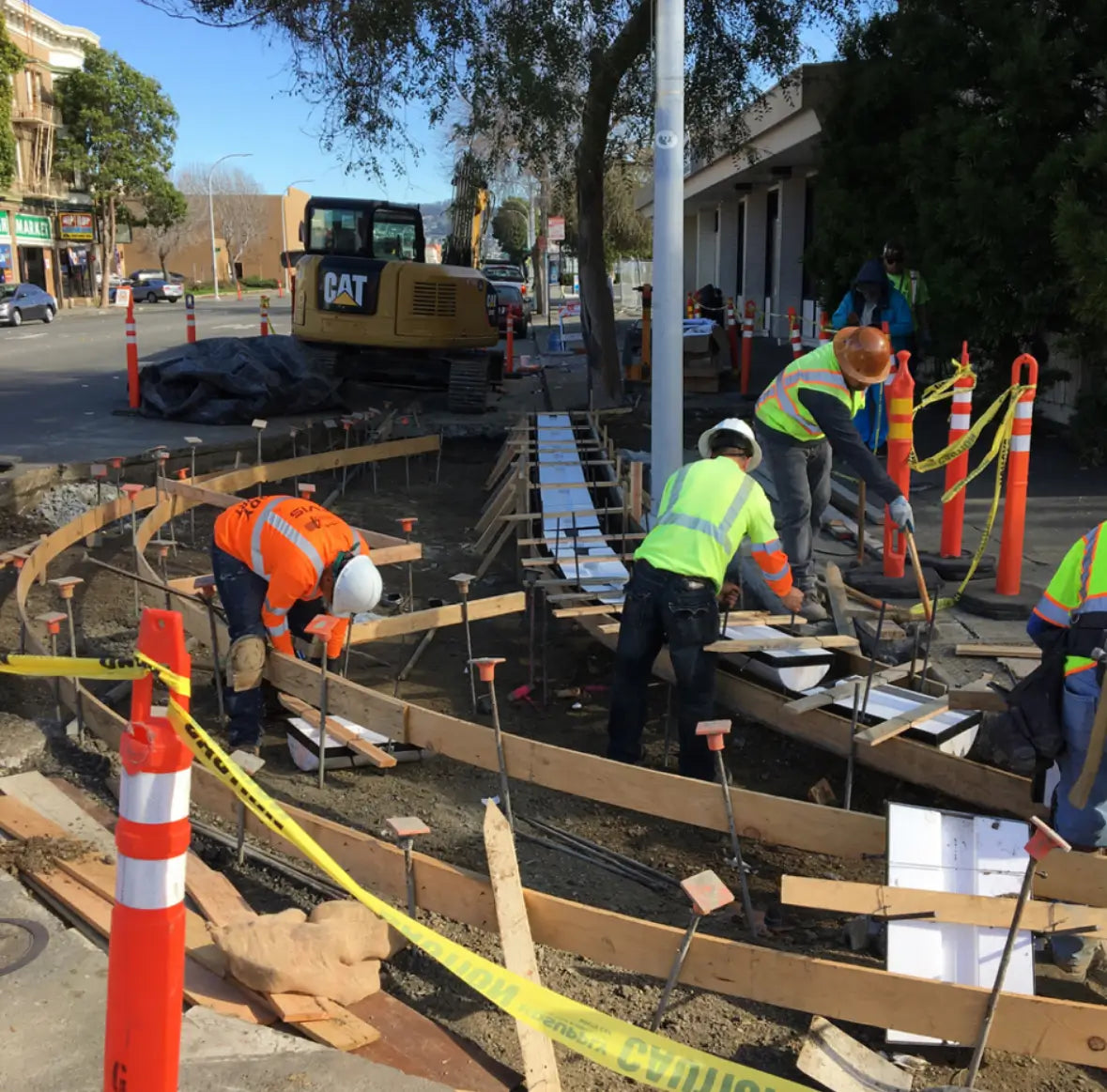Construction workers on a road project with equipment and safety cones.