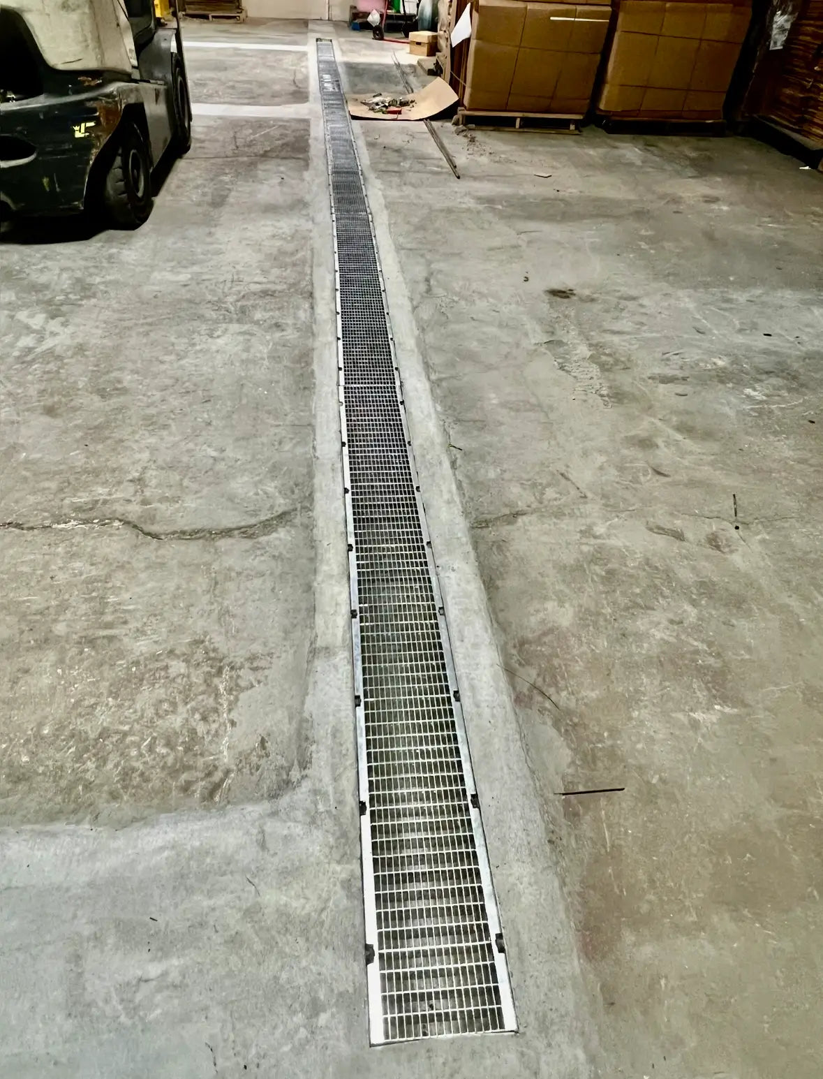 Metal grate on a concrete floor with a vehicle in the background